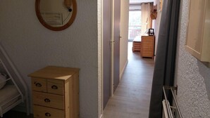 A narrow hallway with a wooden dresser, a mirror, and a radiator. - 50m from resort center, 3rd floor, balcony, parking, tv, ski locker, 32m², Les 2 Alpes (Les Deux Alpes)