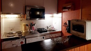 A kitchen with a microwave, toaster, and stove. - 50m from resort center, 3rd floor, balcony, parking, tv, ski locker, 32m², Les 2 Alpes (Les Deux Alpes)