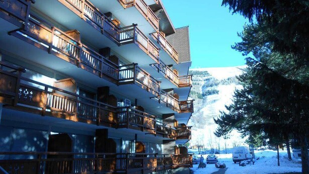 A multi-story hotel with balconies, a snow-covered ground, and a mountain in the background. - 50m from resort center, 3rd floor, balcony, parking, tv, ski locker, 32m², Les 2 Alpes (Les Deux Alpes)