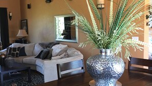 Ein Wohnzimmer mit einer Couch, einem Couchtisch, einem Esstisch und einer dekorativen Vase mit Pflanzen.