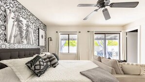 A bedroom with a large bed, a ceiling fan, and a view of the outdoors through a window. -  Desert Escape w/Pool/Jacuzzi (Palm Desert)