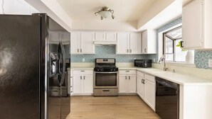 A modern kitchen with white cabinets, a stainless steel refrigerator, an oven, and a dishwasher. -  Desert Escape w/Pool/Jacuzzi (Palm Desert)