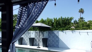 A pool area with a patterned wall, a trash bin, and a ceiling fan. -  Desert Escape w/Pool/Jacuzzi (Palm Desert)