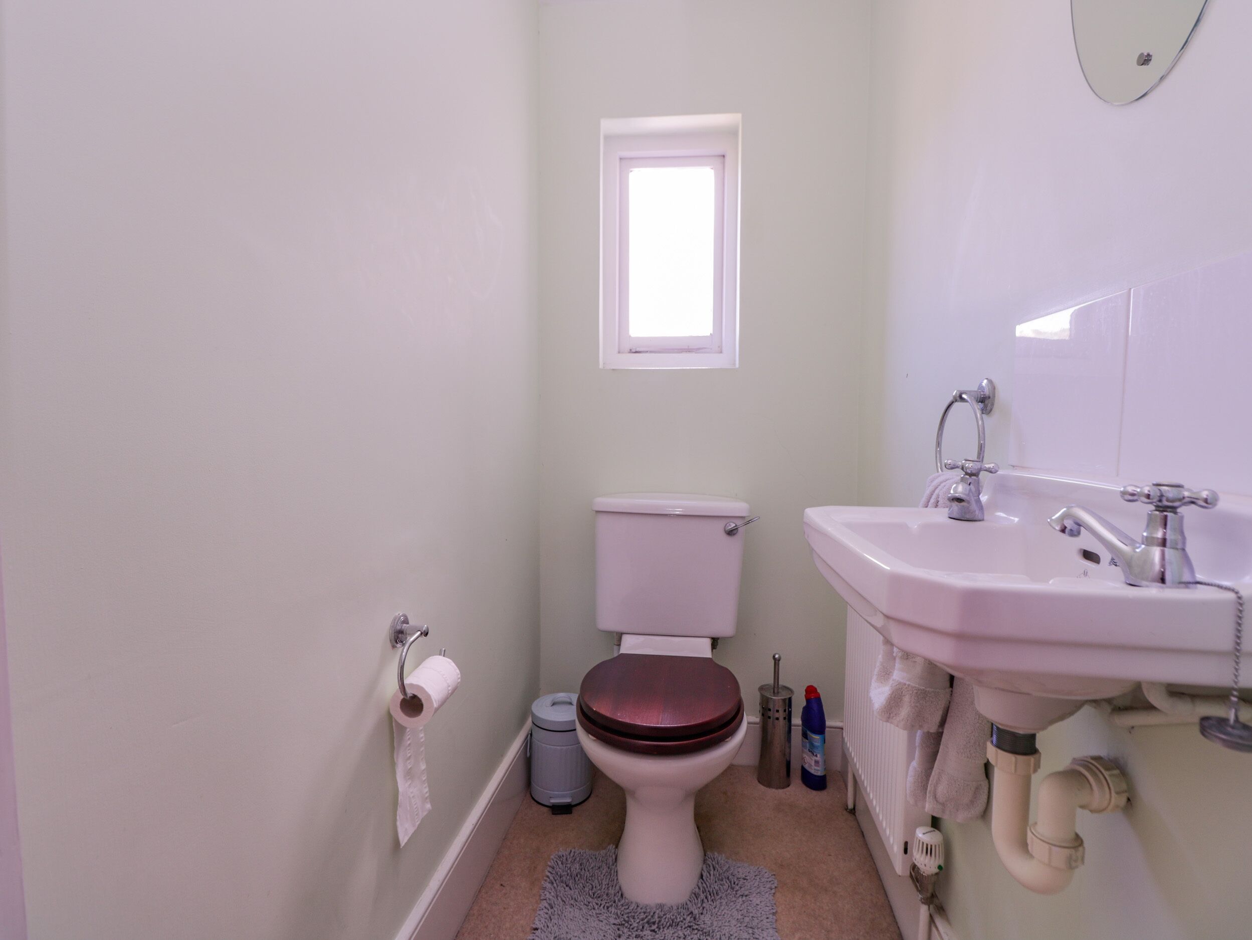 A small bathroom with a toilet, sink, and window.