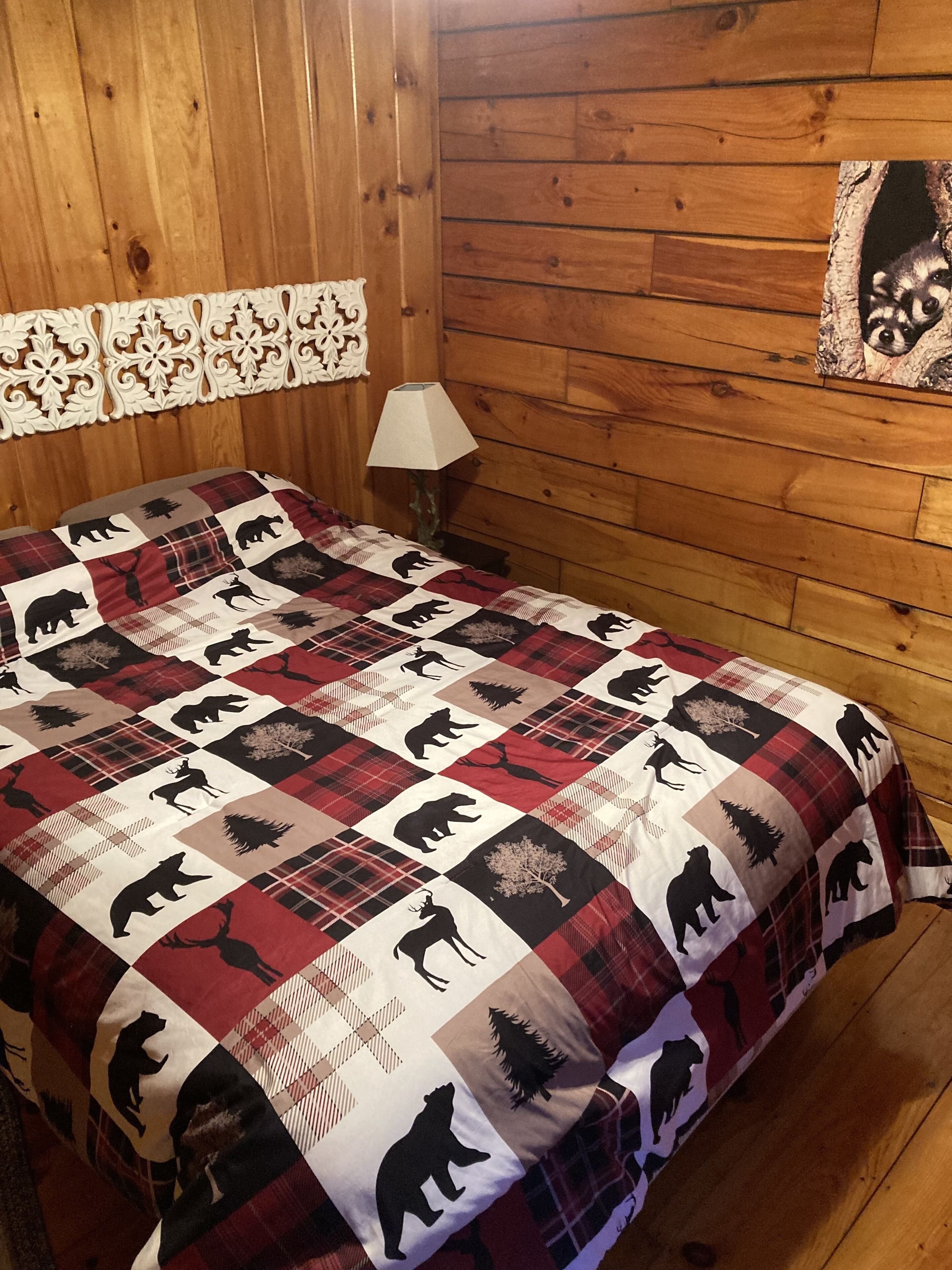 Une chambre dans un chalet en bois, avec un lit recouvert d’une courtepointe ornée de motifs animaliers.