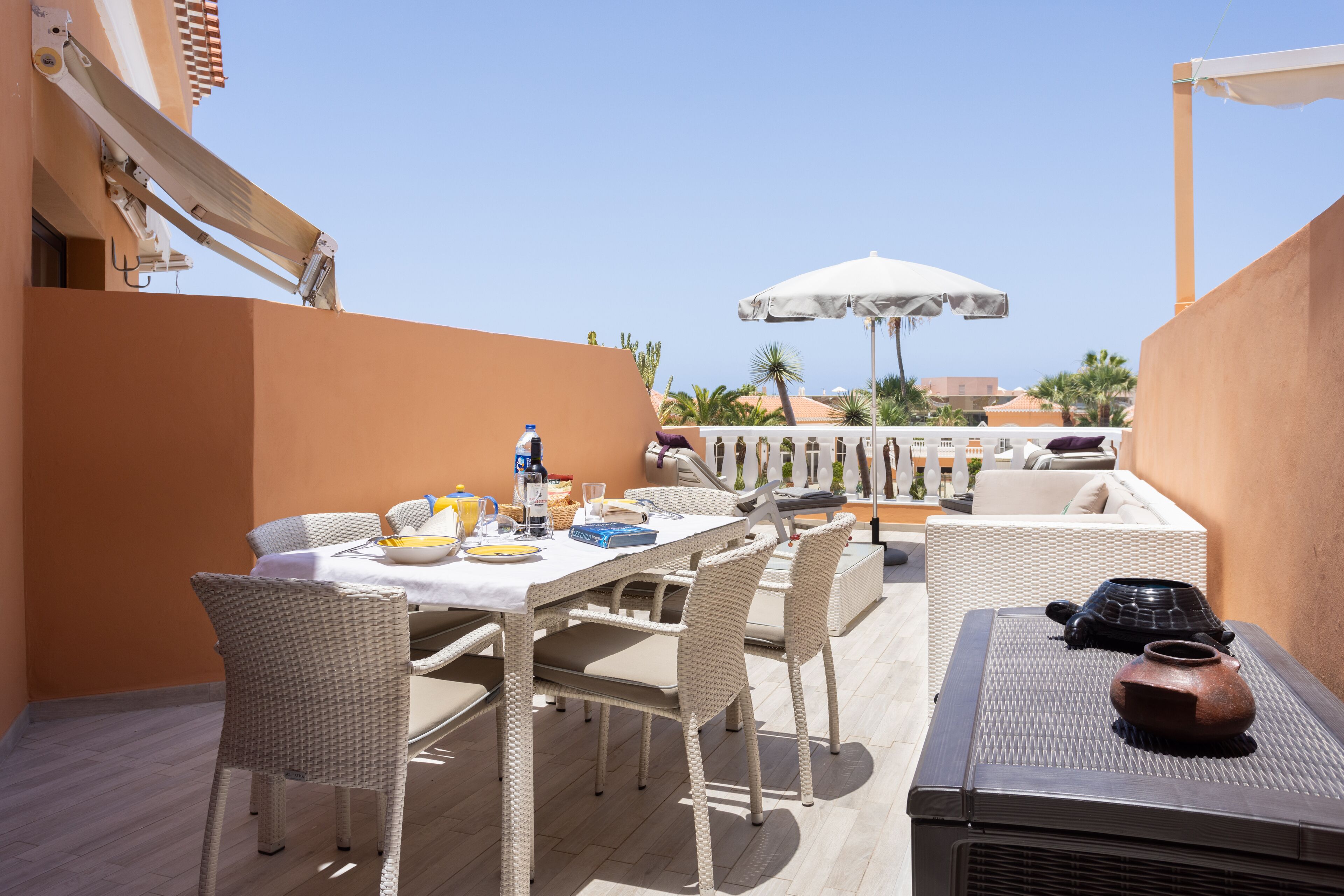 Un patio al aire libre con mesa, sillas y una sombrilla grande.