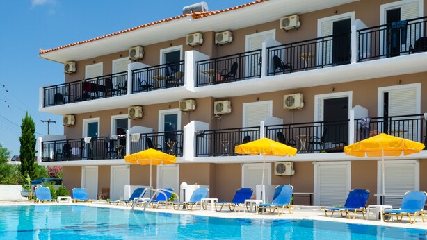 Un hôtel doté d’une piscine, de plusieurs balcons et d’un espace extérieur aménagé avec des parasols.
