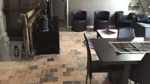 A loft-style room with a brick floor, a dining table with chairs, and a sofa. - Gîte Holsteiner (domaine de la Marchandaie) - 3 stars (Angrie)
