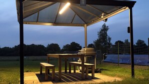A covered outdoor seating area with tables and benches, a grill, and a canopy. - Gîte Holsteiner (domaine de la Marchandaie) - 3 stars (Angrie)