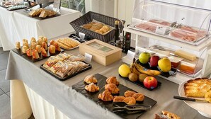 Een buffettafel met diverse gerechten, waaronder gebak, belegde broodjes, fruit en een grill.