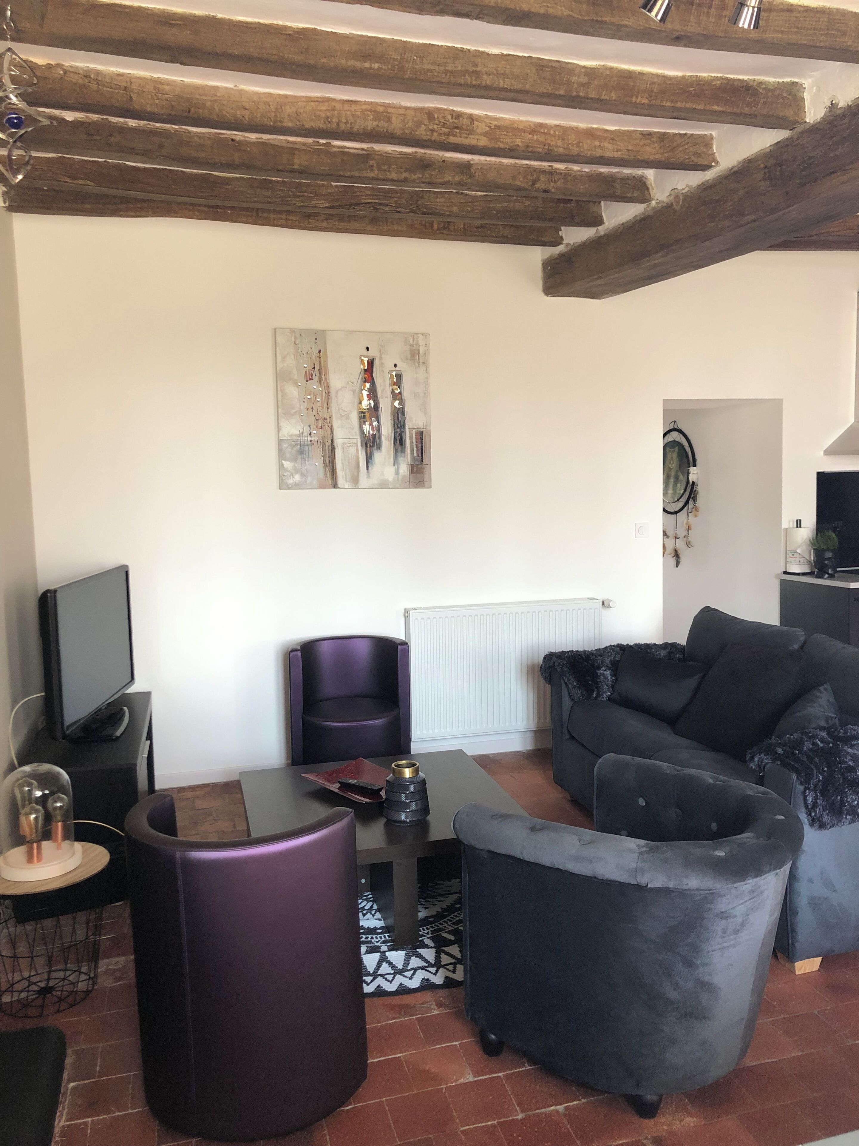 Ein Wohnzimmer mit einer Couch, Sesseln, einem Couchtisch und einem Fernseher.