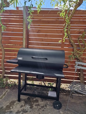 A black outdoor grill with a handle, positioned on a concrete surface.