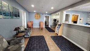 A modern interior with a seating area, a clock on the wall, and a counter with a sign. - Star of The Lakes (Detroit Lakes)