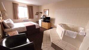 A hotel room with two beds, a sofa, a TV, a microwave, and a bathtub. - Star of The Lakes (Detroit Lakes)