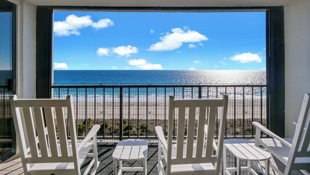 A balcony with white chairs and a view of the ocean. - Station One 6F - a beautifully updated 2 bedroom condo (Wrightsville Beach)