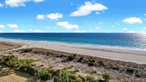 A beach with a clear sky, sandy shore, and sparse vegetation. - Station One 6F - a beautifully updated 2 bedroom condo (Wrightsville Beach)