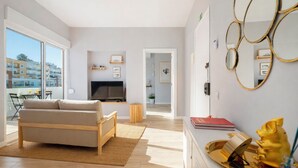 Een moderne woonkamer met een bank, televisie en een eetgedeelte met tafel en stoelen.