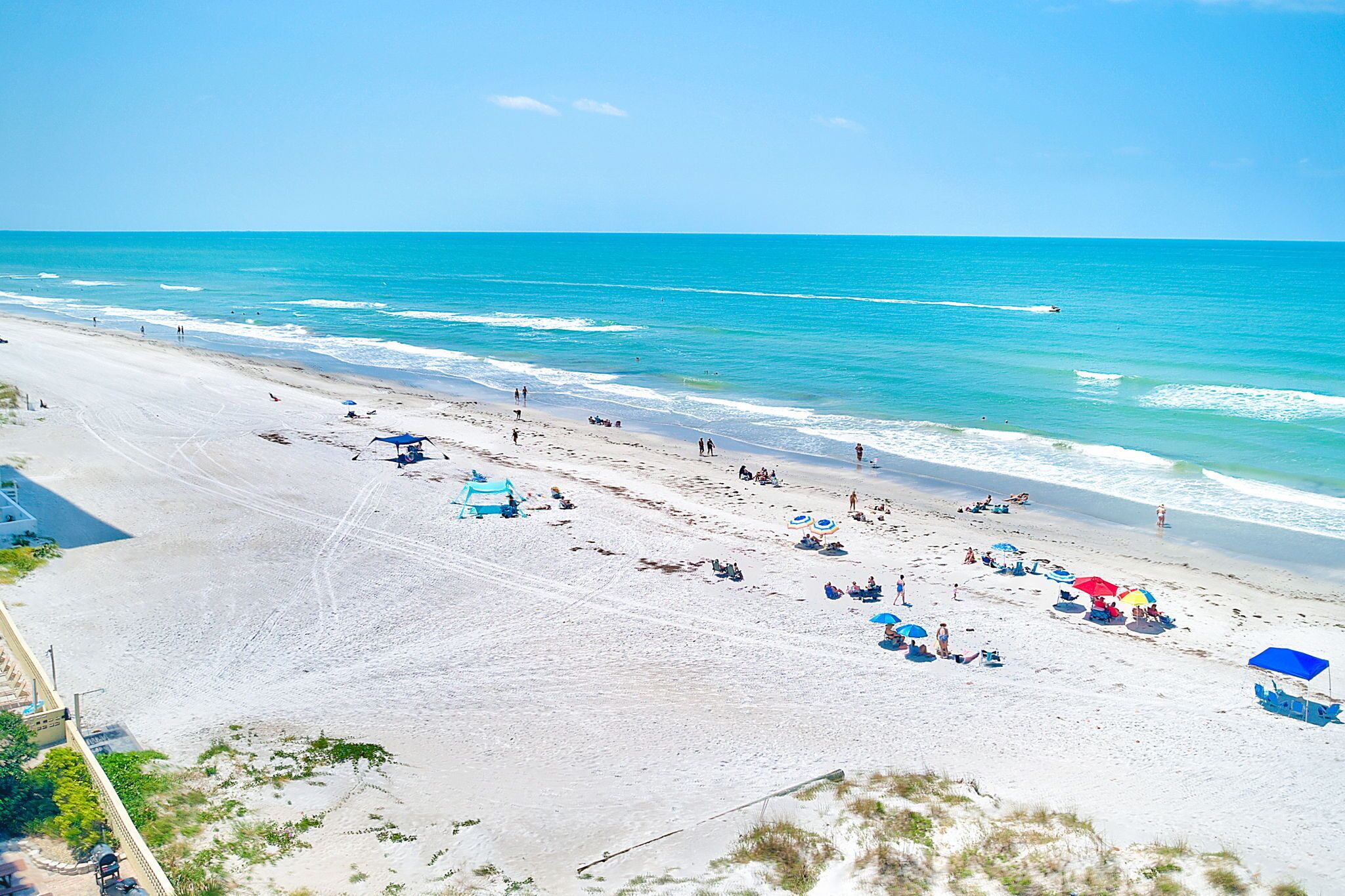 A beach with clear skies, a sandy shore, and a few umbrellas and beach chairs.