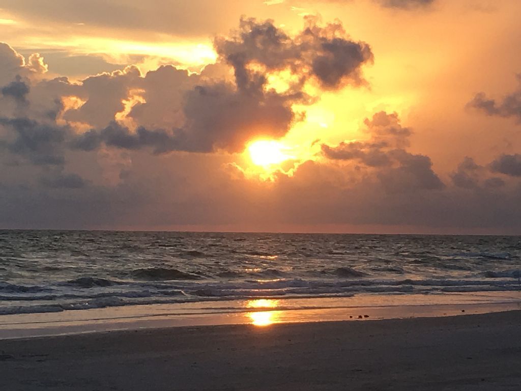 A sunset over the ocean with clouds in the sky.