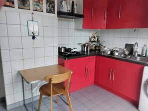 A kitchen with red cabinets, a wooden table, and a hanging light fixture.