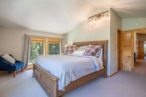 Un dormitorio con una cama de madera, una silla y un ventanal con cortinas.