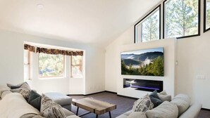 Una sala de estar con un sofá, una mesa de centro y un televisor montado en la pared.