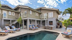 A two-story residential building with a swimming pool, outdoor seating, and a covered patio area.