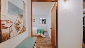 A narrow hallway leading to a bedroom with a bed, a window, and a wall-mounted picture. - Baker View Lodging with hot tub, sound, mountain, and territorial views. (Camano)