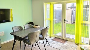 A dining area with a table and chairs, a television mounted on the wall, and a sliding glass door leading to a backyard. - 3 bed (2 bath) whole home with free parking - 3 miles from Edinburgh airport (Edinburgh)