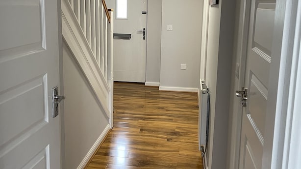 A hallway with wooden flooring, white doors, and a staircase with a wooden railing. - 3 bed (2 bath) whole home with free parking - 3 miles from Edinburgh airport (Edinburgh)