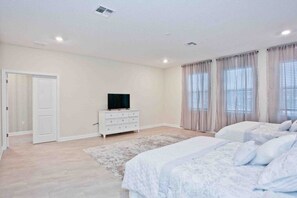 Relax in this serene bedroom with a large bed, flat-screen TV, and a convenient door to the adjacent room.