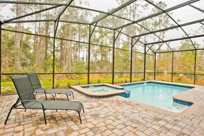 Relax by the pool with a hot tub and lounge chairs in a serene outdoor setting.