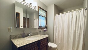 A bathroom with a double sink vanity, a toilet, and a shower curtain. - Relaxing 3 Bedroom Home in Lake Community (Albrightsville)