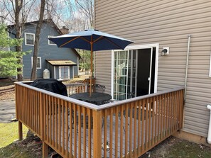 A wooden deck with a table and chairs, a grill, and a covered umbrella. - Relaxing 3 Bedroom Home in Lake Community (Albrightsville)