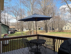 A deck with a table and chairs, an umbrella, and a view of houses and trees. - Relaxing 3 Bedroom Home in Lake Community (Albrightsville)