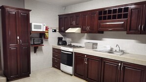 Una cocina con armarios de madera oscura, una estufa blanca, un microondas y una cafetera.