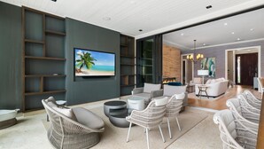 Een moderne woonkamer met een flatscreen televisie, rieten meubels, een open haard en een groot raam.