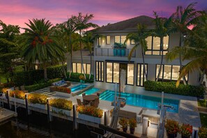 A modern two-story house with a swimming pool, outdoor seating, and lush landscaping. - LUXURIOUS MANSION WITH 5 SUITES ON THE WATER!! (Fort Lauderdale)
