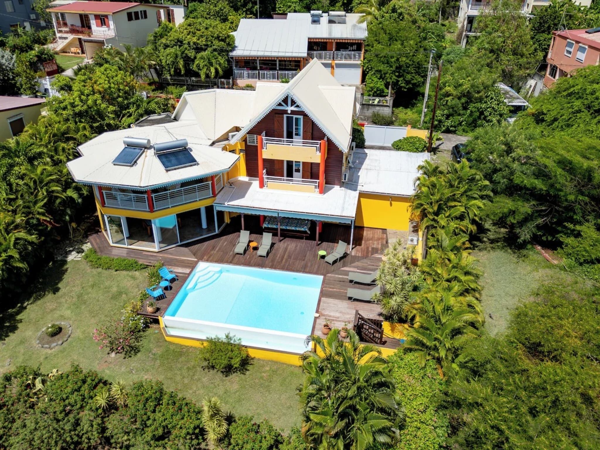 Ein großzügiges Haus mit Swimmingpool, mehreren Terrassen und üppiger Bepflanzung.