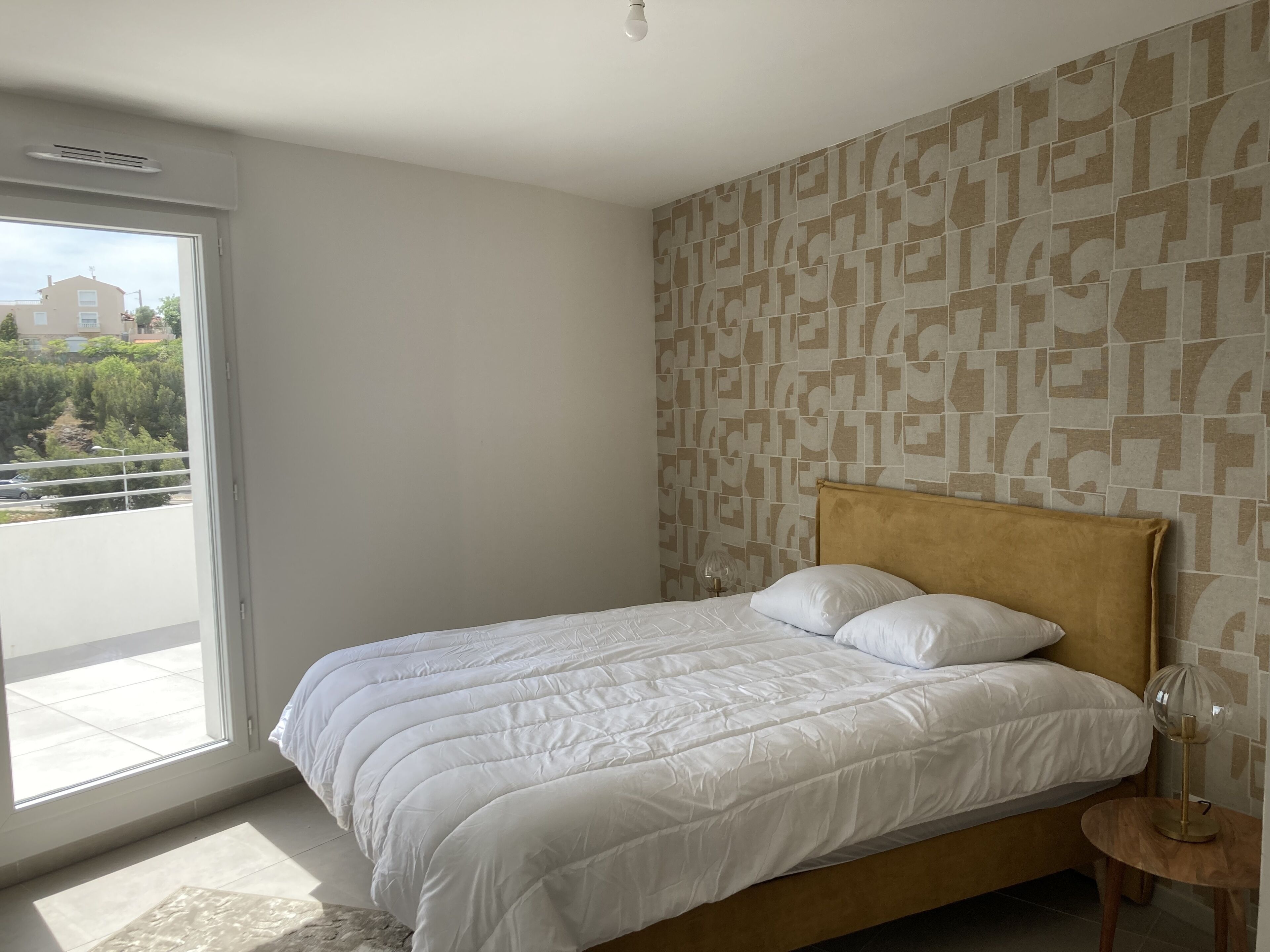 A bedroom with a bed, a window, and a patterned wall.