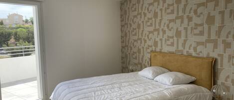 A bedroom with a bed, a window, and a patterned wall.