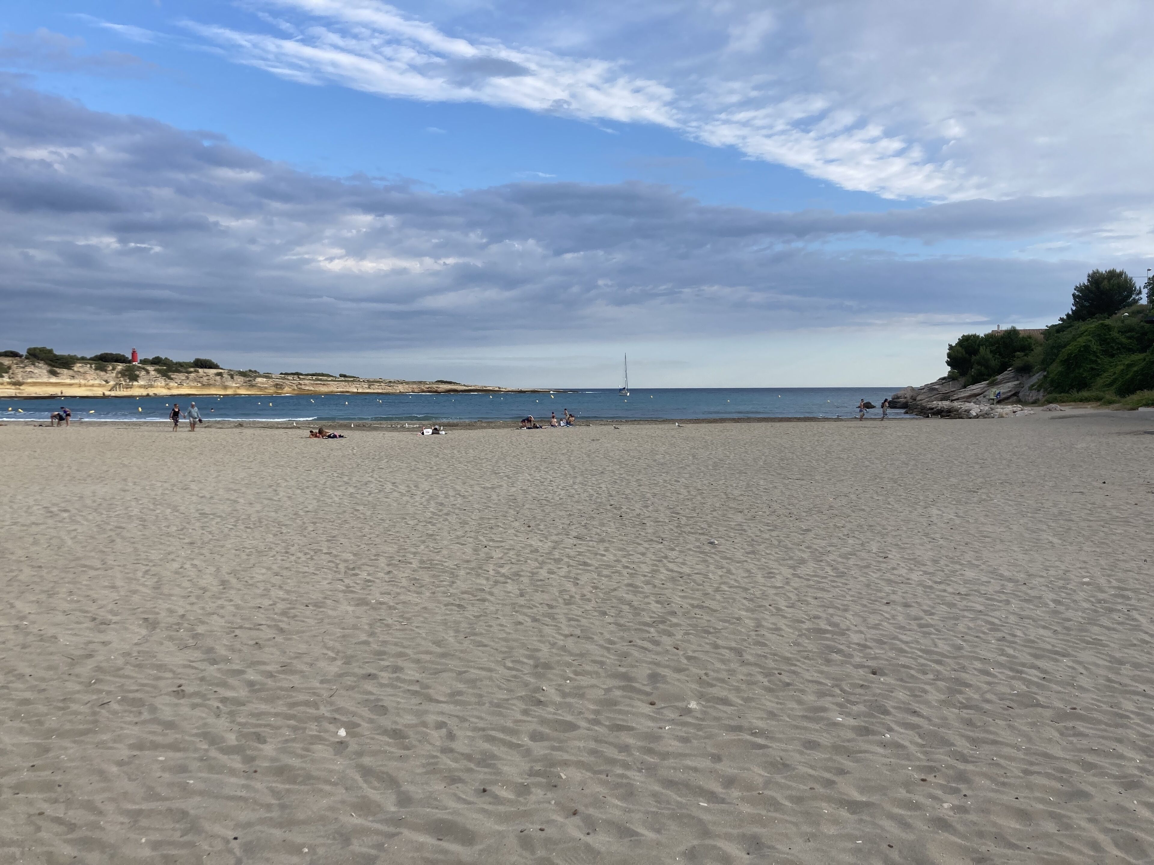 A wide sandy beach with a clear view of the sea and distant hills.