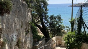 A stone staircase leading down to a coastal area with a clear view of the sea.