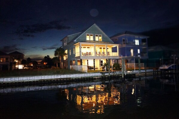 A waterfront property with a large house featuring a balcony and a pool.