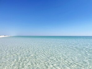 A clear blue sea with a sandy beach.