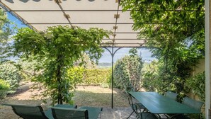 A covered patio with a table and chairs, surrounded by greenery and a view of the countryside. - 2-BEDROOM TOWNHOUSE WITH NICE VIEW (N°552) (La Motte)