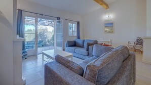 A spacious living room with a grey sofa set, a white coffee table, and a dining area with a white table and chairs. - 2-BEDROOM TOWNHOUSE WITH NICE VIEW (N°552) (La Motte)