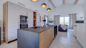 Een moderne keuken met een centraal eiland, houten kastjes en hanglampen.