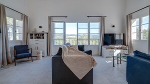 Een ruime woonkamer met een groot bed, een televisie en een balkon met uitzicht.