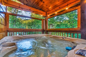 A hot tub with a view of a forest through a wooden deck. - Game Room, Hot Tub, & 3 King Beds, Dogs Welcome (Sevierville)